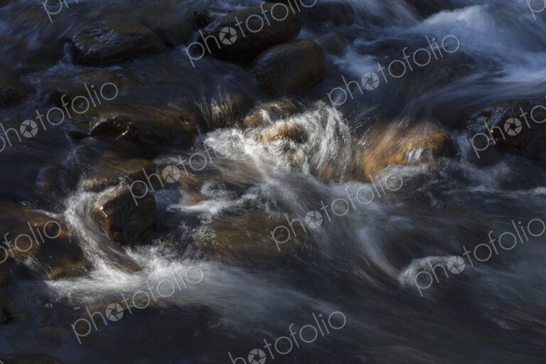 River water abstract, long exposure of river water flowing over boulders and rocks