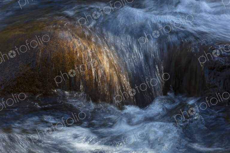 River water abstract, long exposure of river water flowing over boulders and rocks