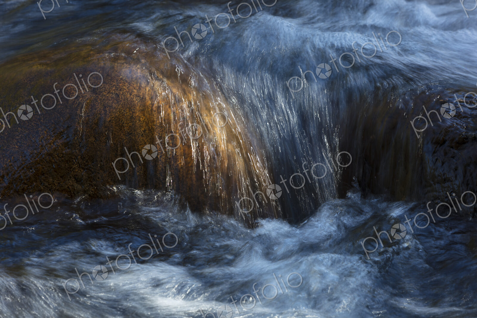 River water abstract, long exposure of river water flowing over boulders and rocks