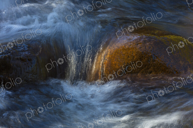 River water abstract, long exposure of river water flowing over boulders and rocks