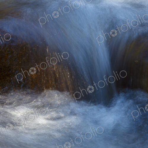 River water abstract, long exposure of river water flowing over boulders and rocks