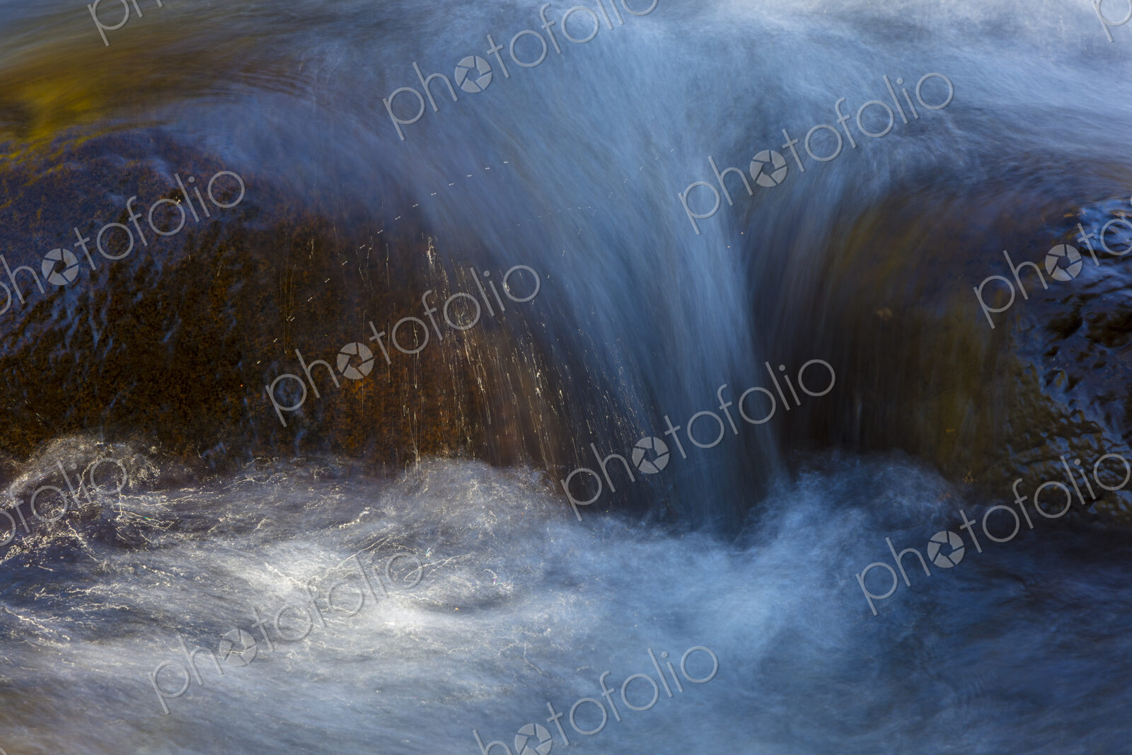 River water abstract, long exposure of river water flowing over boulders and rocks