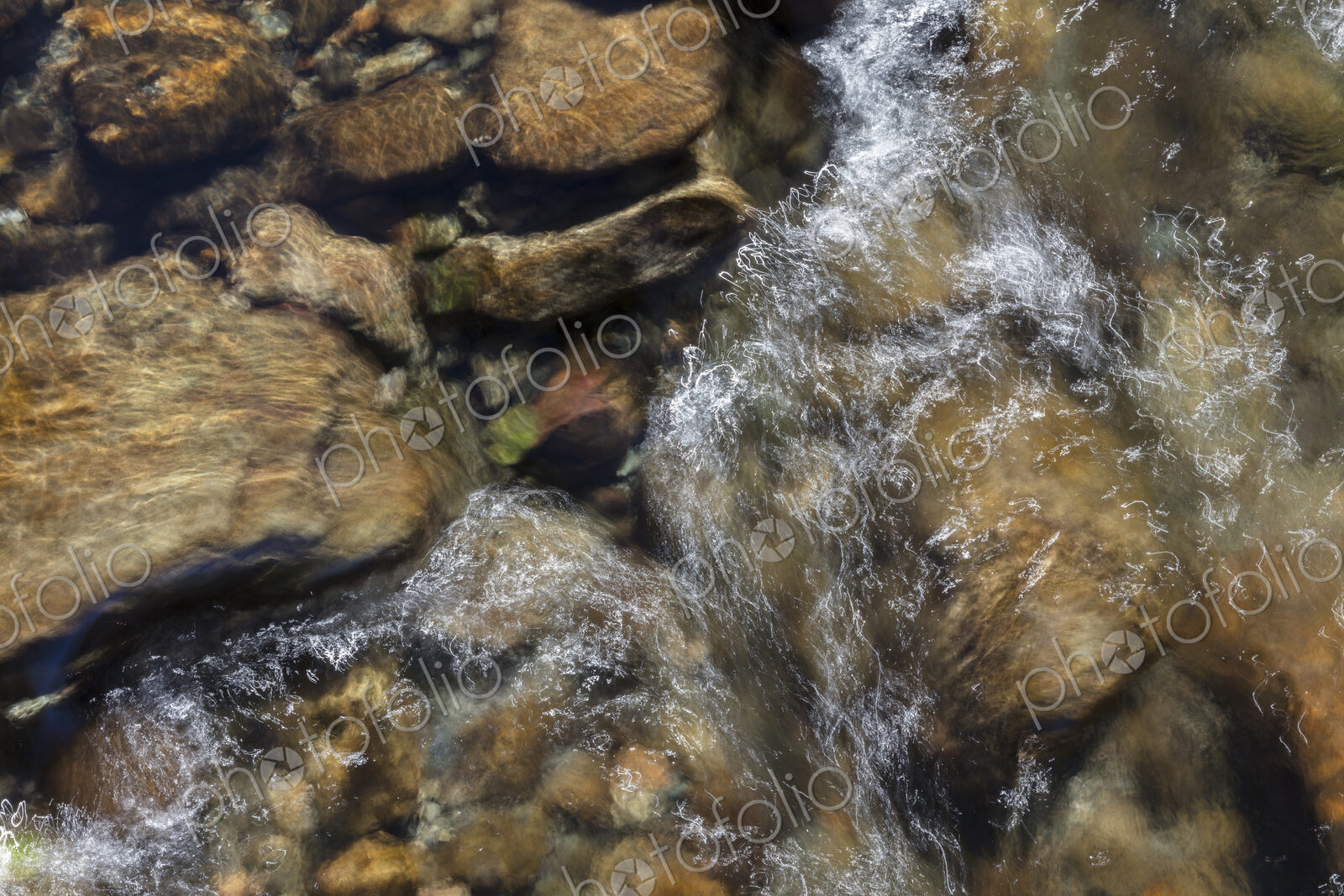 River water abstract, long exposure of river water flowing over boulders and rocks