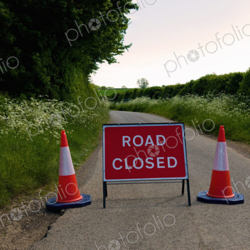 Road Closed sign with two traffic cones on a rural road in summer Road Closed sign with two traffic cones on a rural road in summer