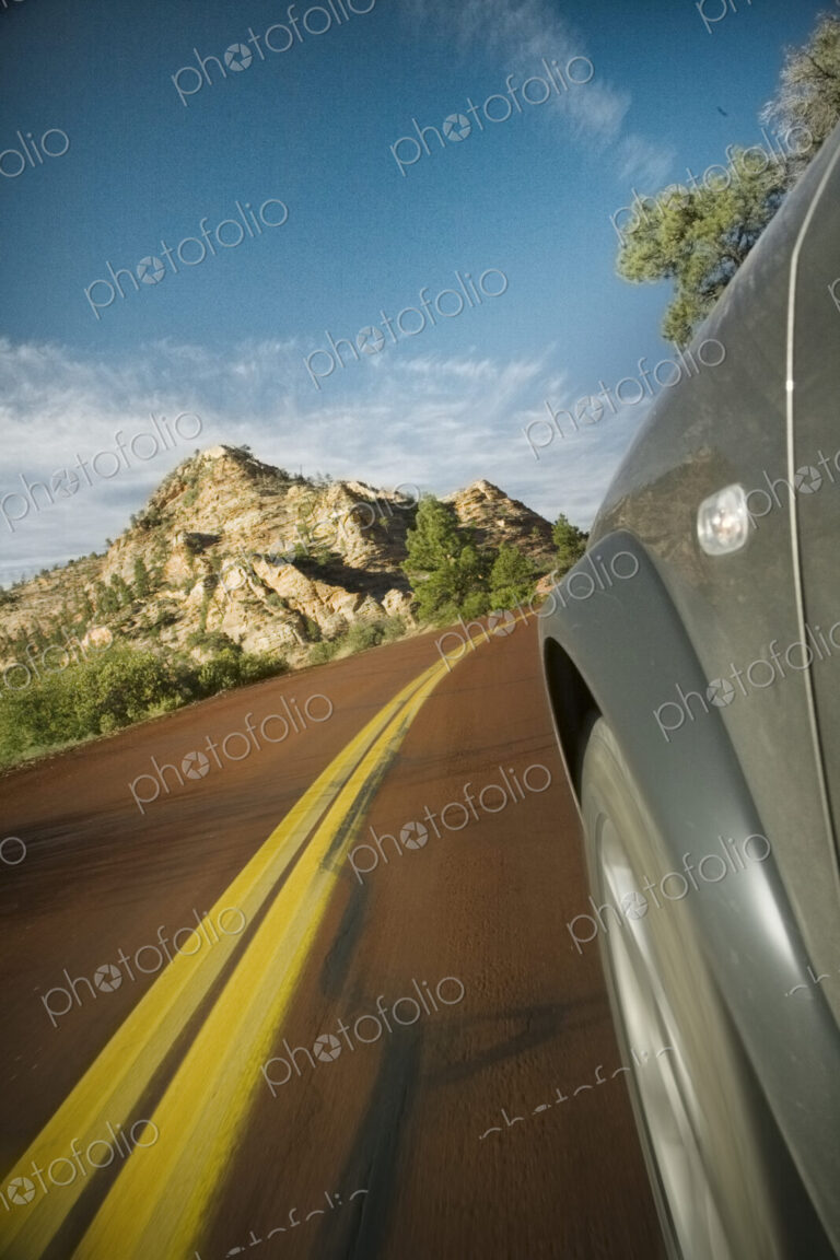Road, a car travelling along, view of wheel arch and yellow road marking