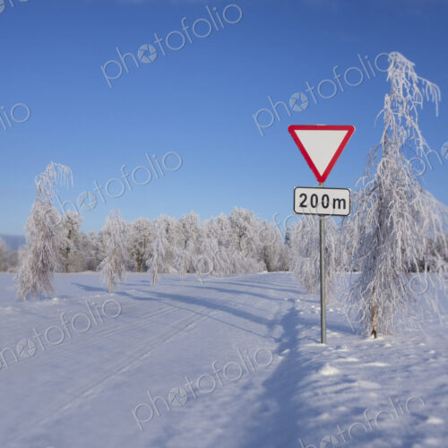 Roadside traffic sign in winter. Give way or yield road sign.