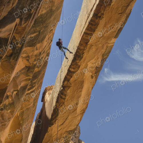 Rock climber hanging on rope on arch Rock climber hanging on rope on arch