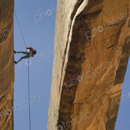 Rock climber using rope on arch