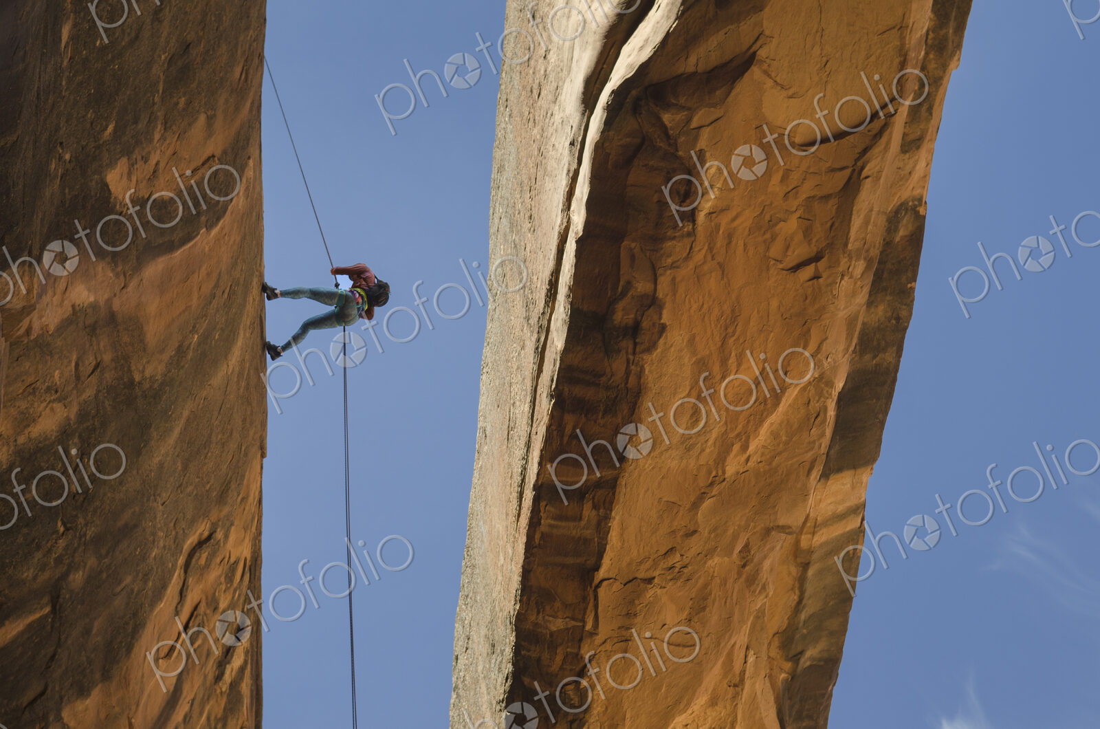 Rock climber using rope on arch