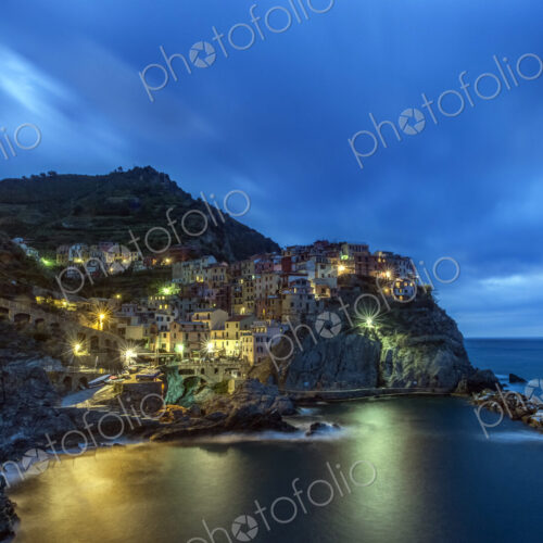 Rocky Manarola coastline illuminated at night, La Spezia, Italy