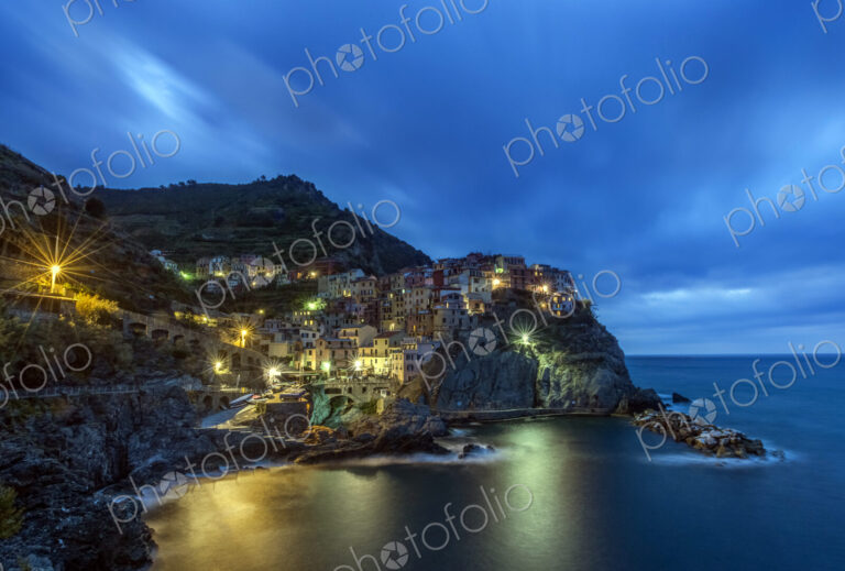 Rocky Manarola coastline illuminated at night, La Spezia, Italy