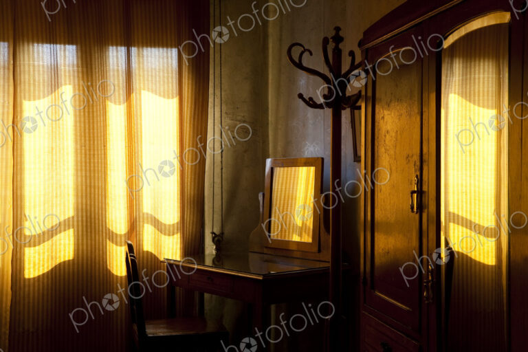 Room interior with vintage wooden dressing table, drawn curtains and sunlight