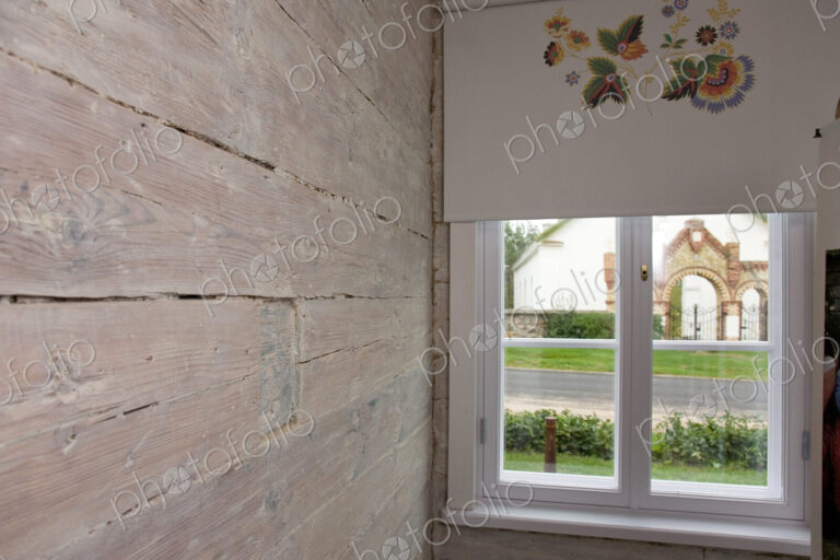 Room with wooden wall and window and patterned window blind.