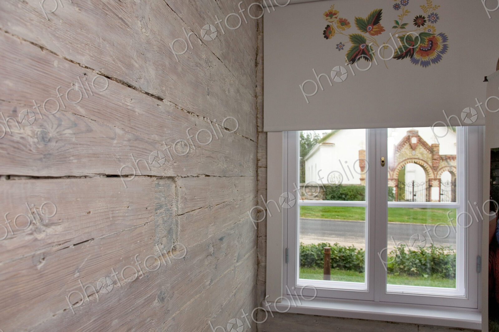 Room with wooden wall and window and patterned window blind.