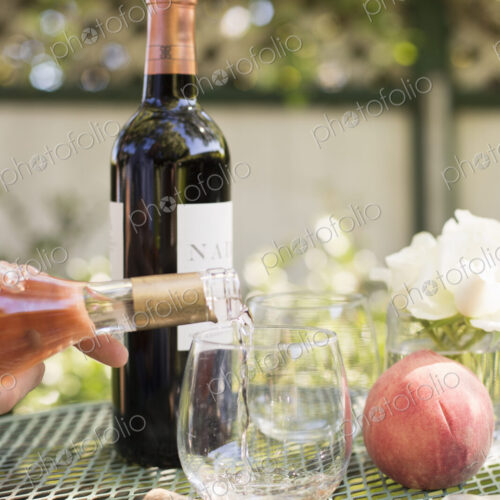 Rose wine being poured from a wine bottle into a glass.