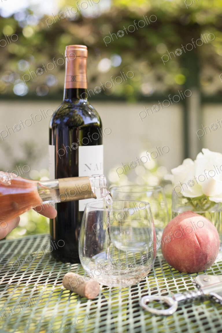 Rose wine being poured from a wine bottle into a glass.