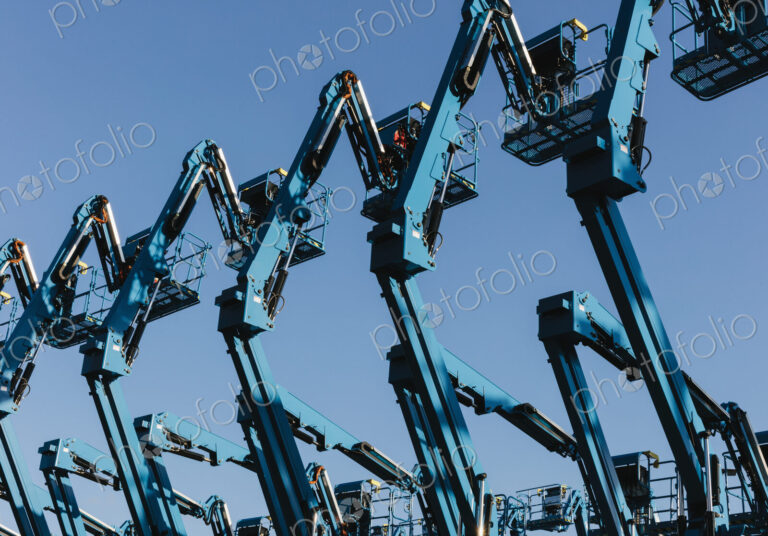 Row of hydraulic mobile cherry picker platforms at outdoor storage facility