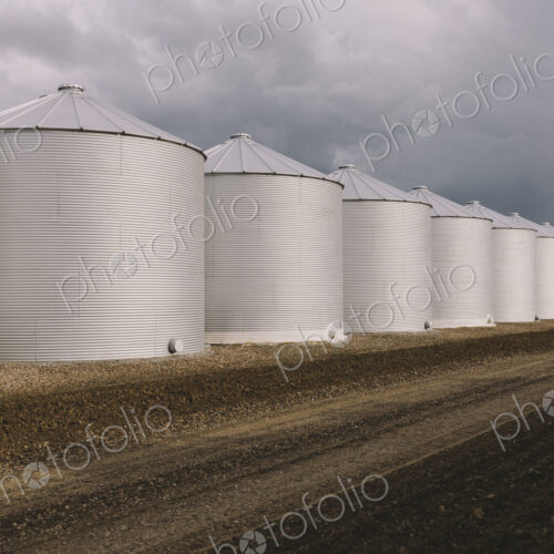 Rows of grain silos, stormy skies in distance, Saskatchewan, Canada.