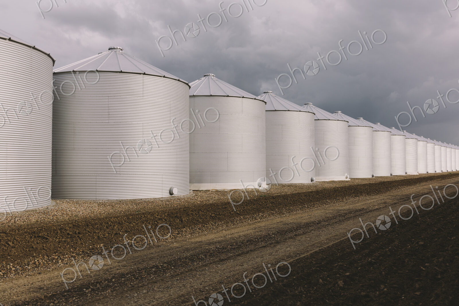 Rows of grain silos, stormy skies in distance, Saskatchewan, Canada.
