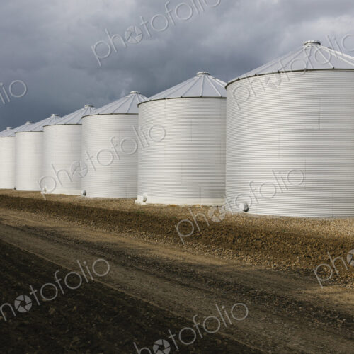 Rows of grain silos, stormy skies in distance, Saskatchewan, Canada.