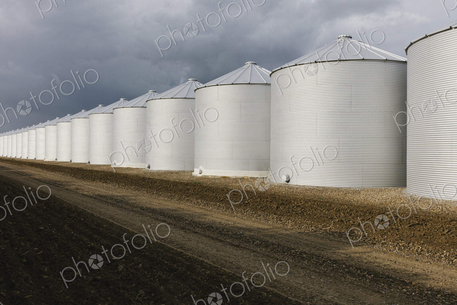 Rows of grain silos, stormy skies in distance, Saskatchewan, Canada.