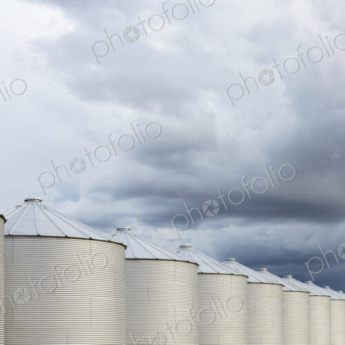 Rows of grain silos, stormy skies in distance, Saskatchewan, Canada.