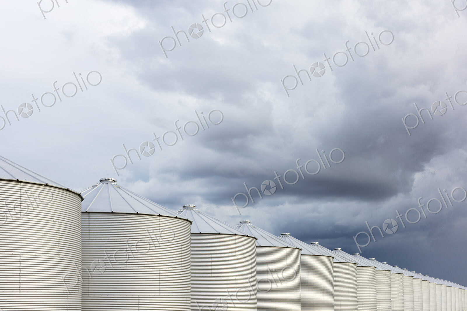 Rows of grain silos, stormy skies in distance, Saskatchewan, Canada.