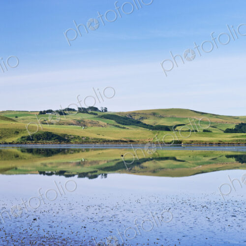 Rural hills reflected in calm estuary Rural hills reflected in calm estuary