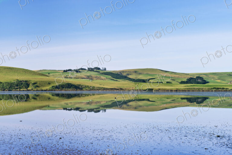 Rural hills reflected in calm estuary
