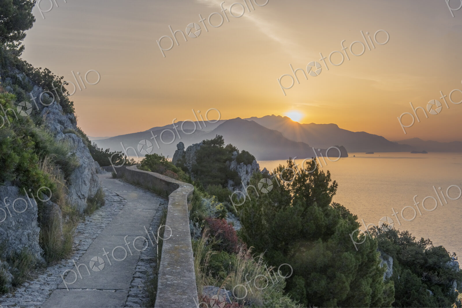 Rural hilltop road with sun rising or setting behind.