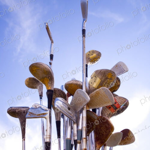Rusted Golf Clubs against a blue sky, wedges, drivers and putters.