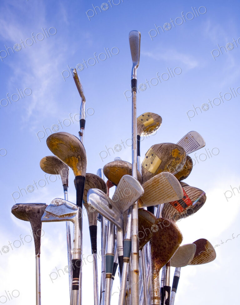 Rusted Golf Clubs against a blue sky, wedges, drivers and putters.