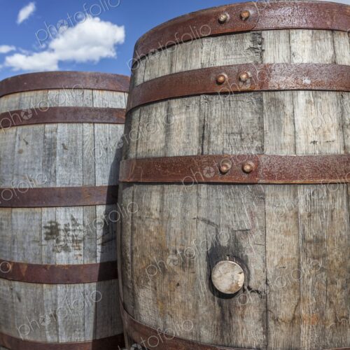 Rustic wooden barrels with metal bands under a bright blue sky in Hill City, South…