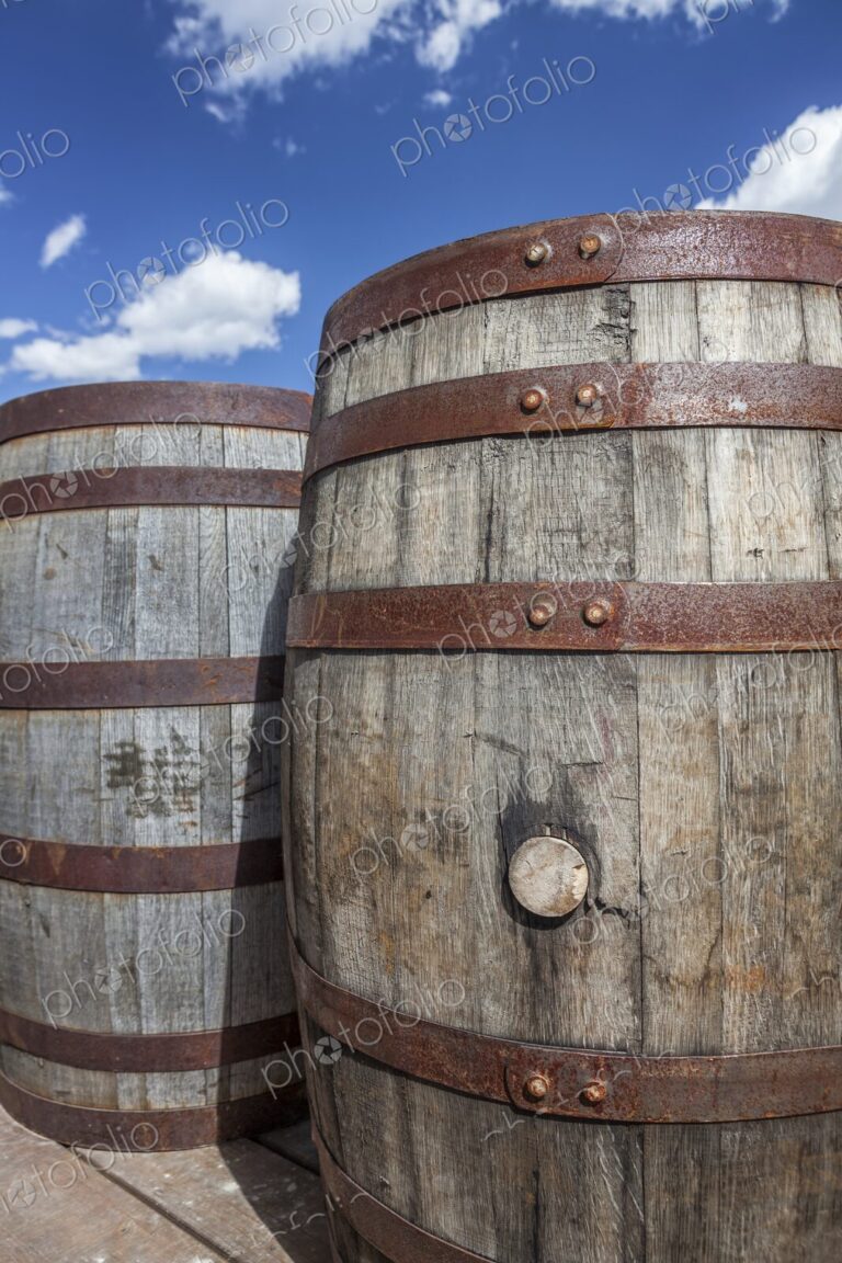 Rustic wooden barrels with metal bands under a bright blue sky in Hill City, South…