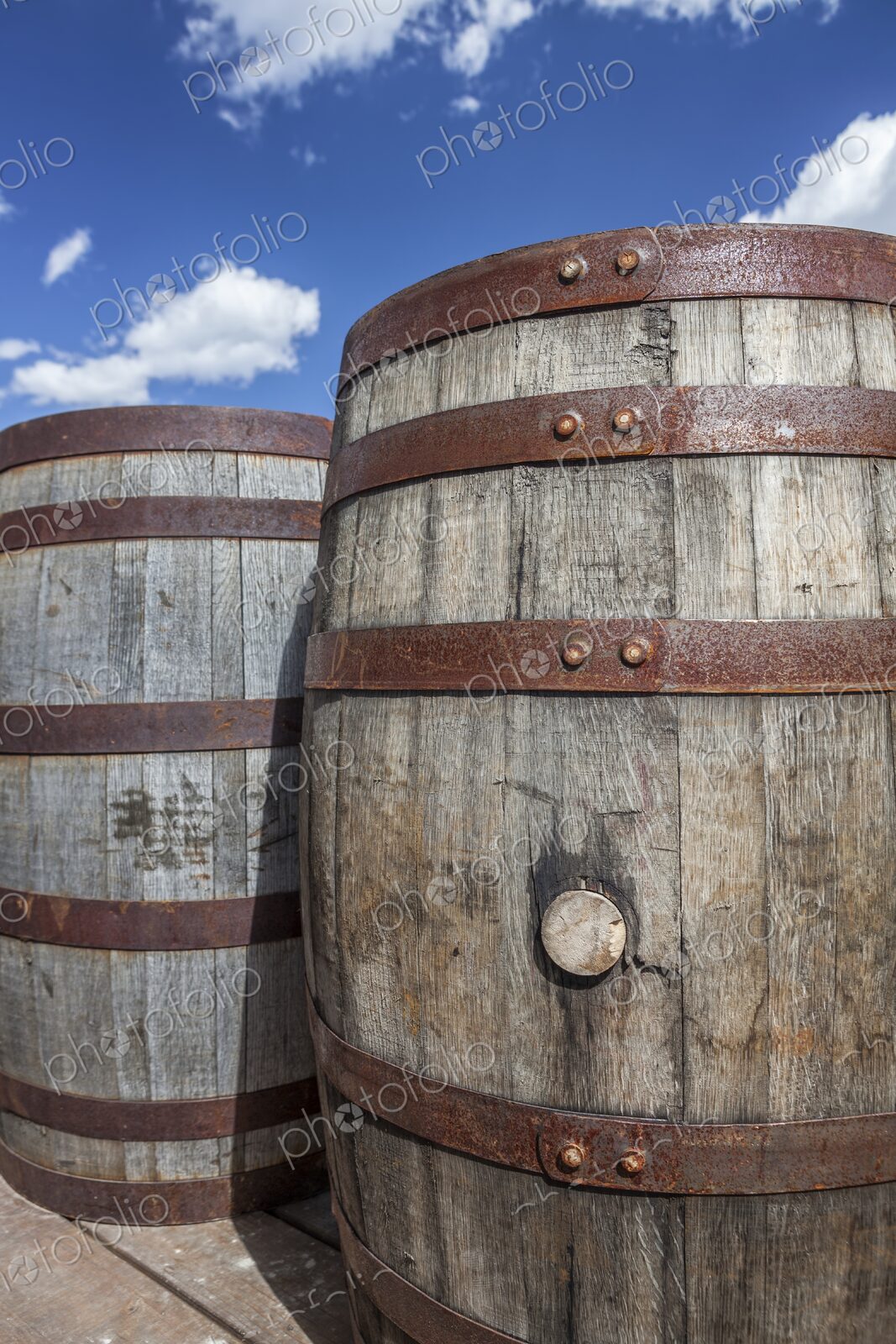 Rustic wooden barrels with metal bands under a bright blue sky in Hill City, South…