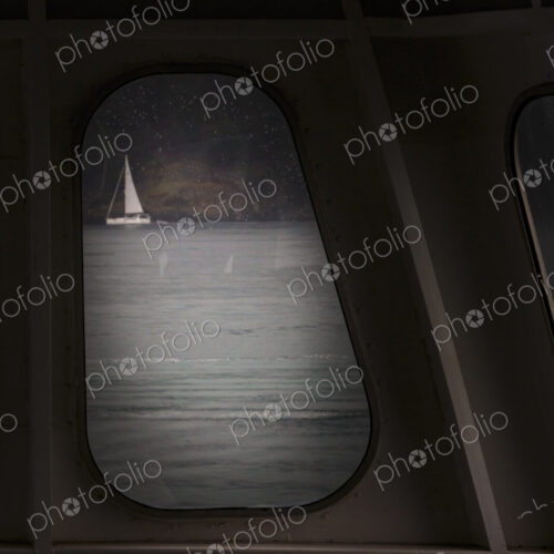 Sailing boat seen through a porthole from a ferry. Sailing boat seen through a porthole from a ferry.