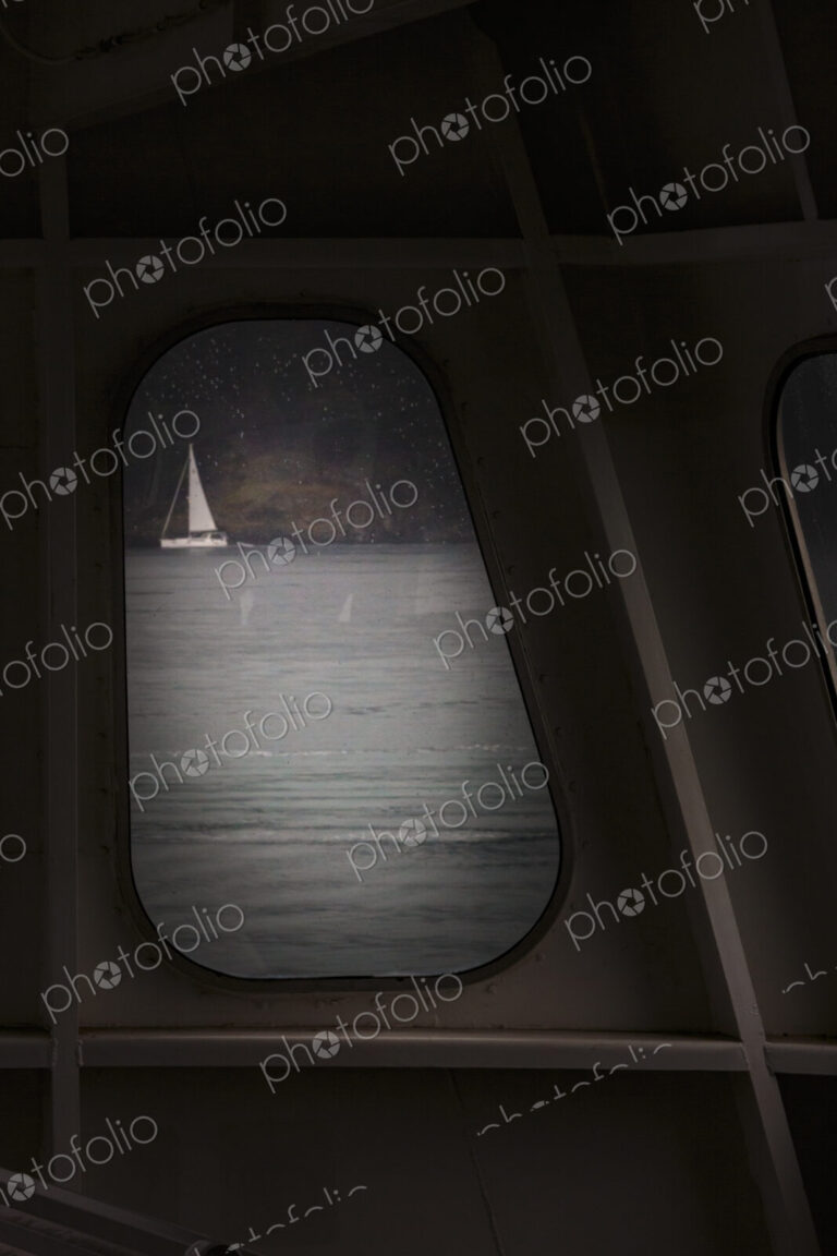 Sailing boat seen through a porthole from a ferry.