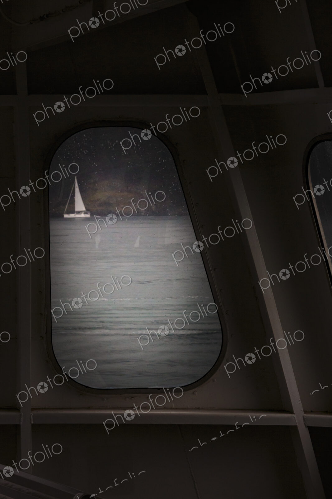 Sailing boat seen through a porthole from a ferry.