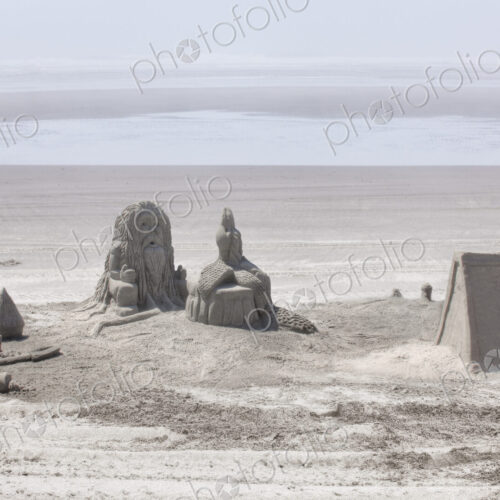Sand castles referencing Native American culture on sandy beach.