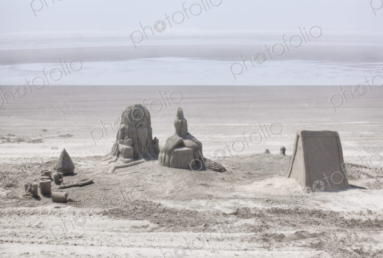 Sand castles referencing Native American culture on sandy beach.