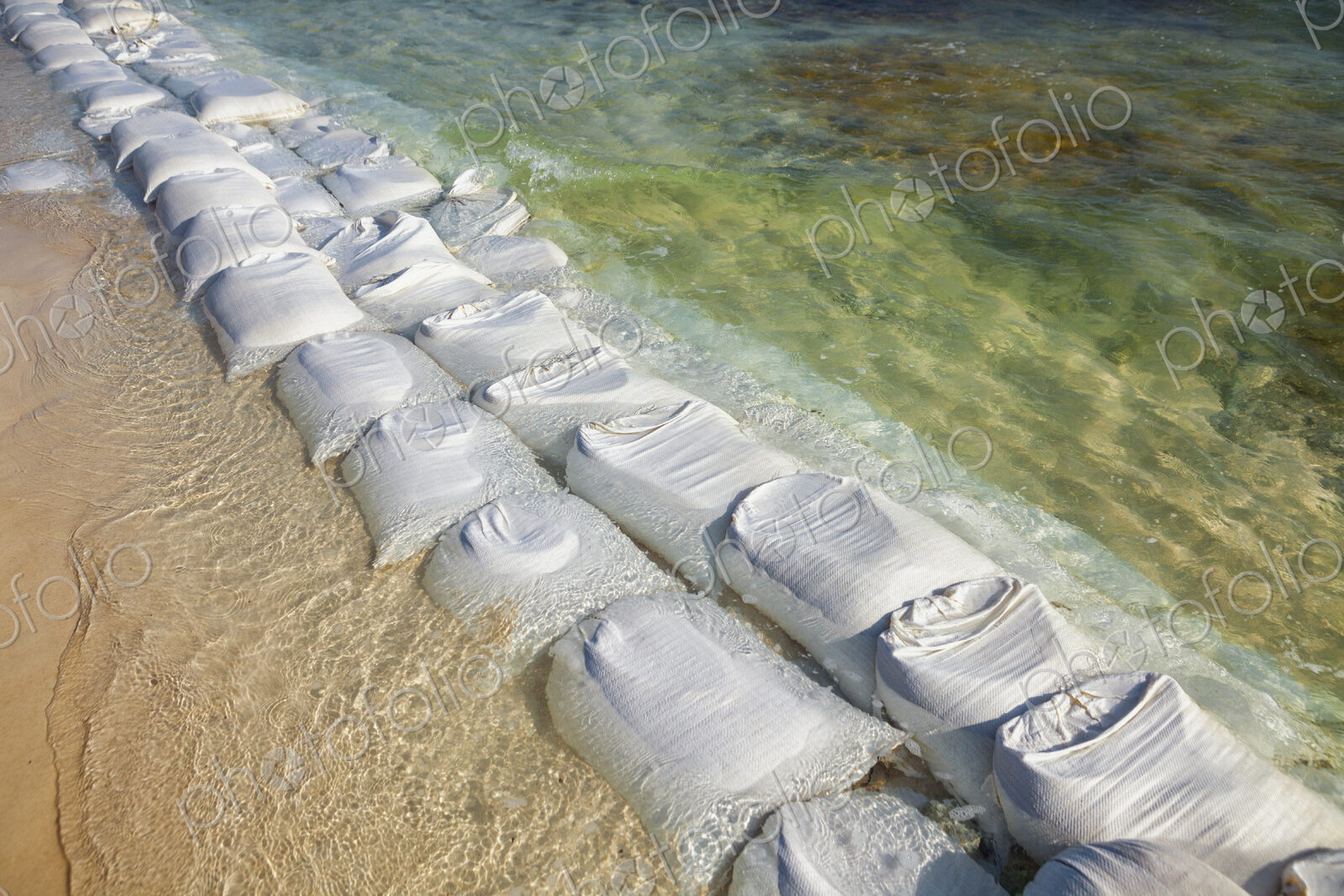 Sandbags in rows at the water’s edge to prevent erosion of the beach