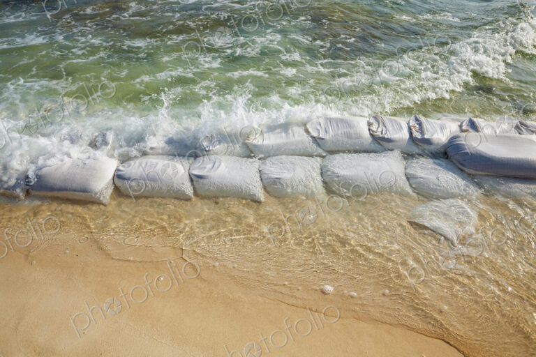 Sandbags in rows at the water's edge to prevent erosion of the beach