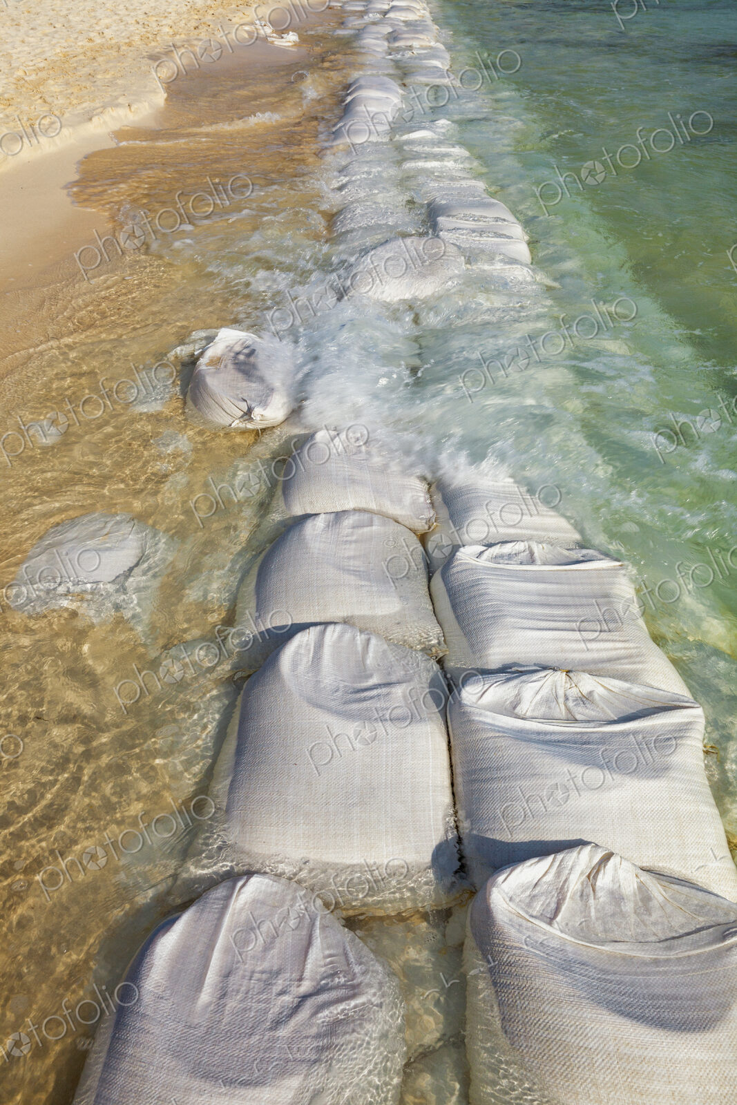 Sandbags in rows at the water’s edge to prevent erosion of the beach