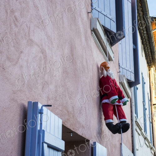 Santa Clause figure hanging on rope from a window of house with pink facade. Santa Clause figure hanging on rope from a window of house with pink facade.