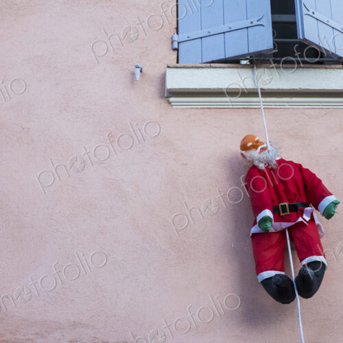 Santa Clause figure hanging on rope from a window of house with pink facade. Santa Clause figure hanging on rope from a window of house with pink facade.