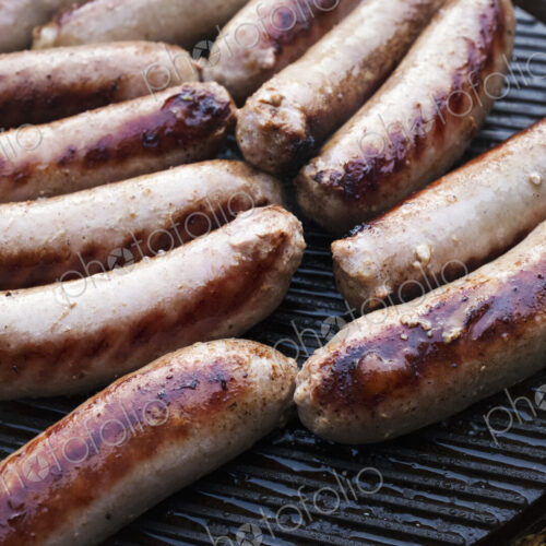 Sausages arranged on top of a barbeque grill, cooking outdoors. Sausages arranged on top of a barbeque grill, cooking outdoors.