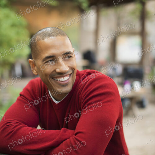 Scenes from urban life in New York City. A man in a red jumper seated at a bench, smiling. Scenes from urban life in New York City. A man in a red jumper seated at a bench, smiling.