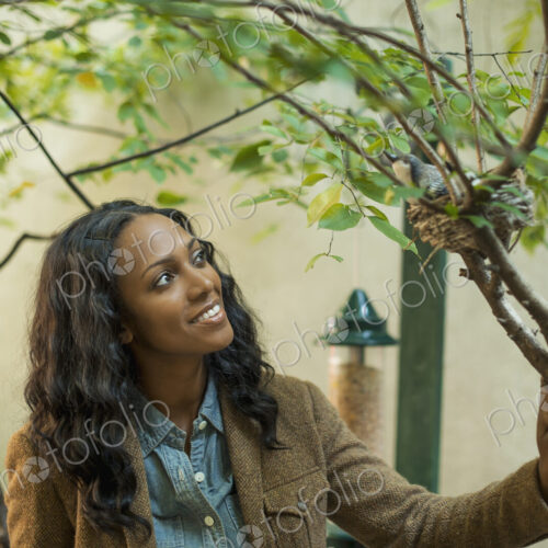 Scenes from urban life in New York City. A woman looking closely at a bird sitting on… Scenes from urban life in New York City. A woman looking closely at a bird sitting on…
