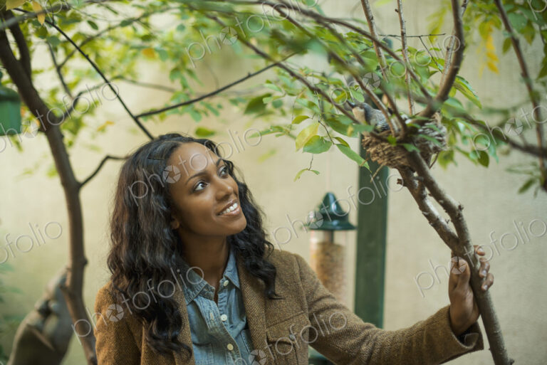 Scenes from urban life in New York City. A woman looking closely at a bird sitting on…