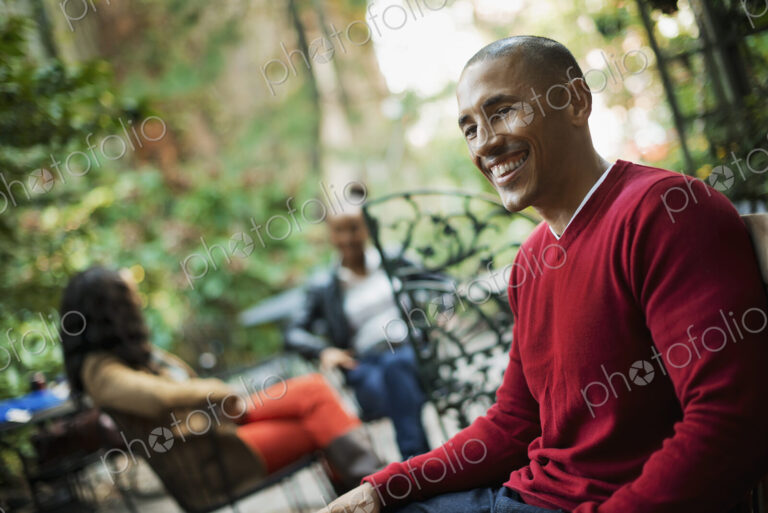 Scenes from urban life in New York City. Three people sitting in an outdoor space.…